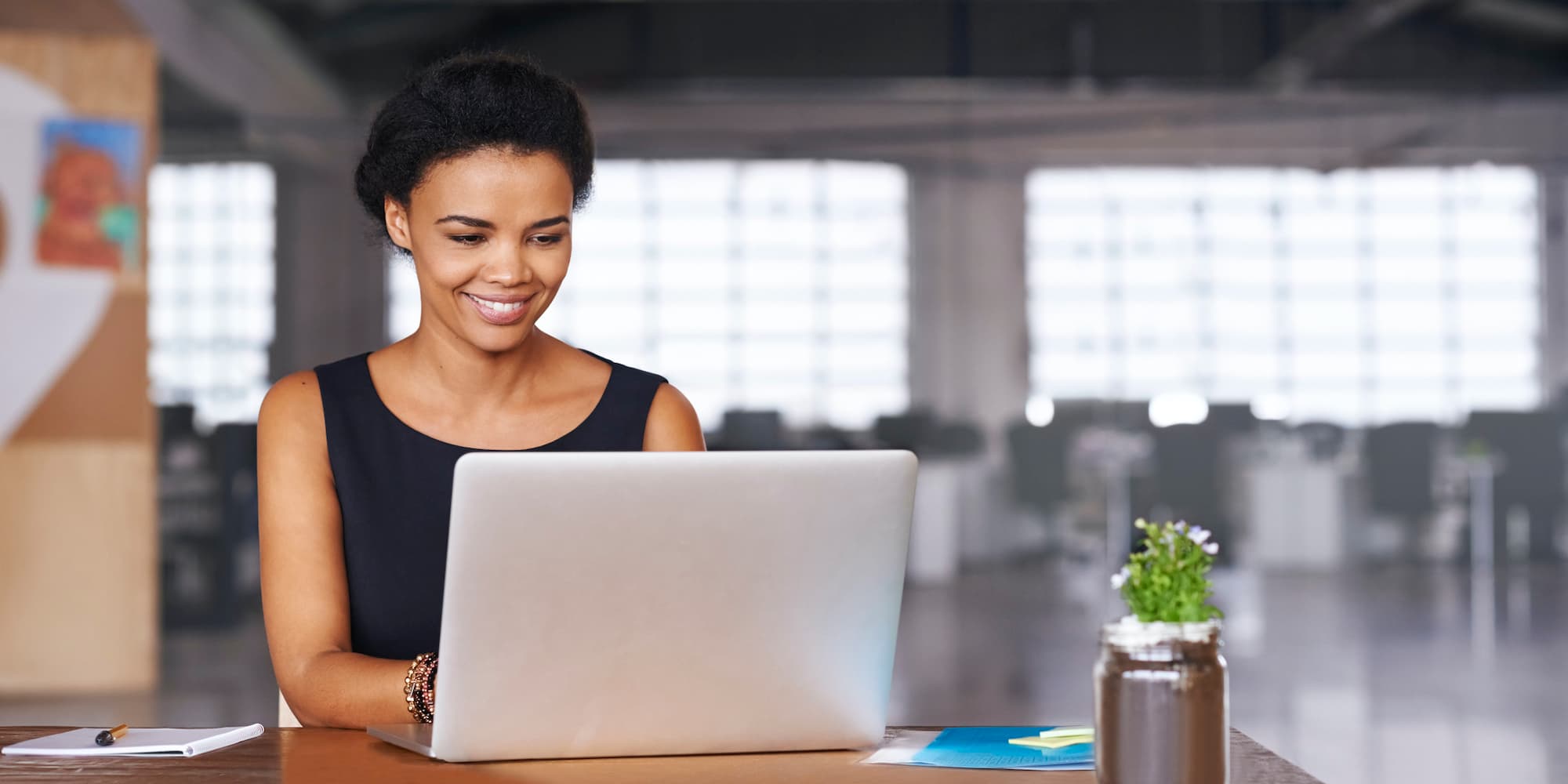 smiling person sitting and working on laptop in office