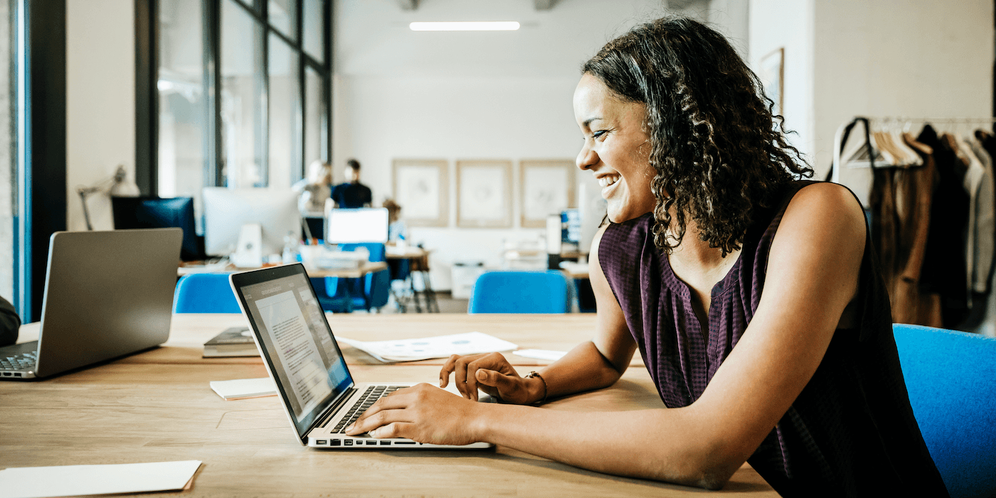 person sitting at a shared table in an office working on a laptop
