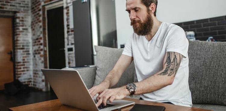 person sitting on a couch typing a cover letter on their laptop